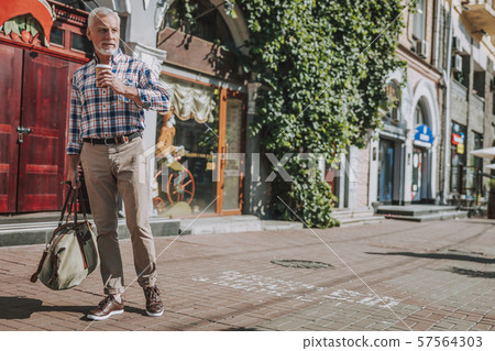 Man with coffee and luggage walking in the street stock photo Man with coffee and luggage walking in the street stock photo 57564303