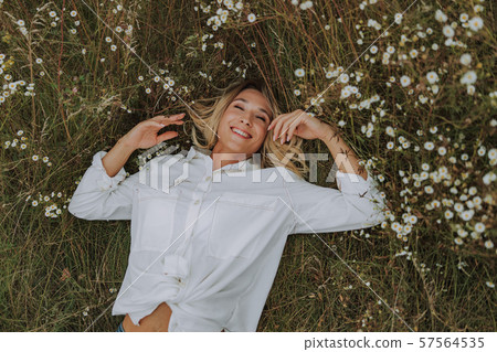 Pretty young woman is lying on grass Pretty young woman is lying on grass 57564535
