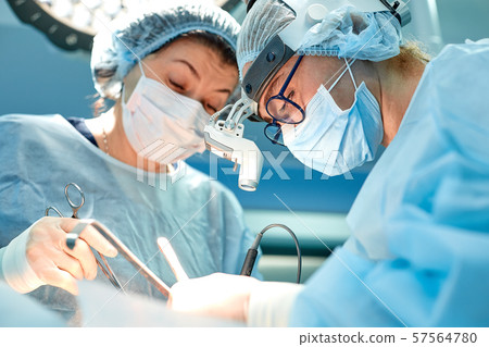 Portrait of team of multiethnic surgeons at work in a operation theatre. Several doctors surrounding Portrait of team of multiethnic surgeons at work in a operation theatre. Several doctors surrounding 57564780