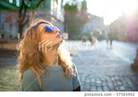 Side view of young woman in blue sunglasses early in the morning in ancient European city on empty 57565002