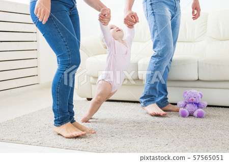 Little baby girl first steps with the help of mom and dad Little baby girl first steps with the help of mom and dad 57565051