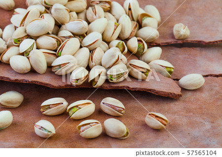 Tasty pistachio nuts on tree rind background Tasty pistachio nuts on tree rind background 57565104