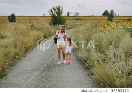 Small Caucasian girl walking with mother on road outdoors Small Caucasian girl walking with mother on road outdoors 57565183