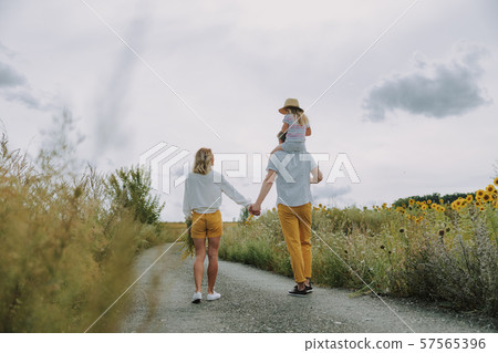 Beautiful young family keeping hands together on the road outdoors Beautiful young family keeping hands together on the road outdoors 57565396
