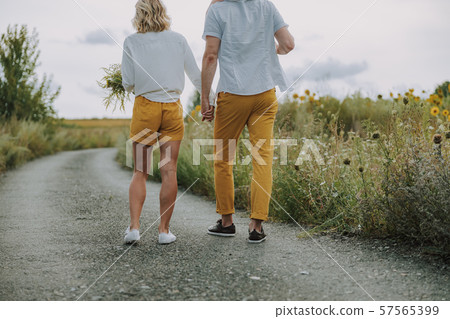 Calm young parents holding hands together on the road outdoors Calm young parents holding hands together on the road outdoors 57565399