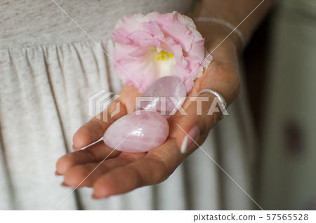 Female hands holding two yoni eggs for vumfit, imbuilding or meditation are made from pink quartz Female hands holding two yoni eggs for vumfit, imbuilding or meditation are made from pink quartz 57565528