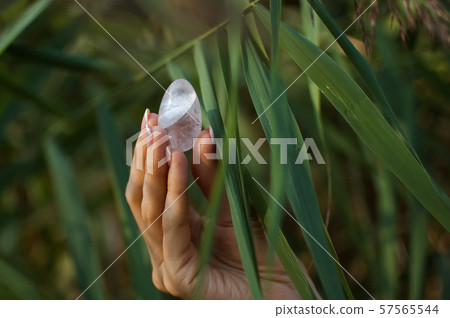 Female hand with french manicure holding transparent violet amethyst yoni egg for vumfit, imbuilding 57565544