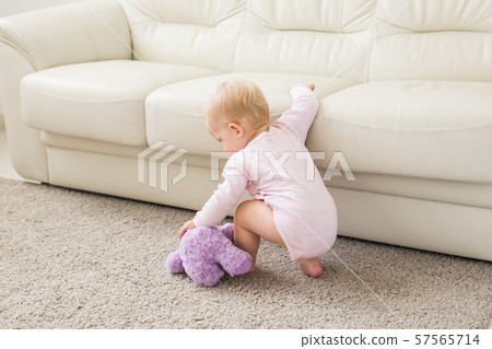 childhood, babyhood and people concept - happy little baby girl playing near couch at home childhood, babyhood and people concept - happy little baby girl playing near couch at home 57565714