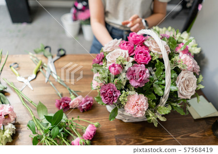 Handsome fresh bouquet. Flowers delivery. Woman florist create flower arrangement in a wicker basket 57568419
