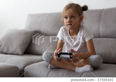 Serious little girl playing video games at home 57569165