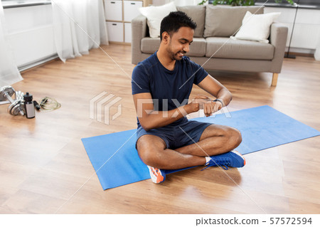 smiling indian man with fitness tracker at home 57572594