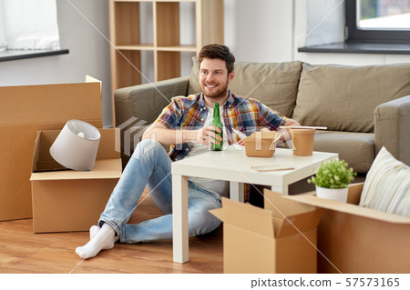 smiling man drinking beer and eating at new home 57573165