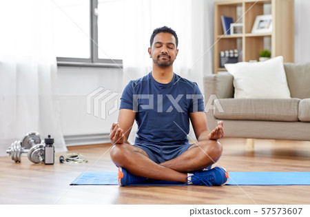 indian man meditating in lotus pose at home indian man meditating in lotus pose at home 57573607