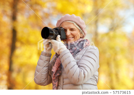 senior woman with photo camera at autumn park senior woman with photo camera at autumn park 57573615