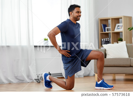 indian man exercising and doing squats at home indian man exercising and doing squats at home 57573618