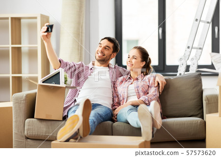 couple taking selfie by smartphone at new home 57573620