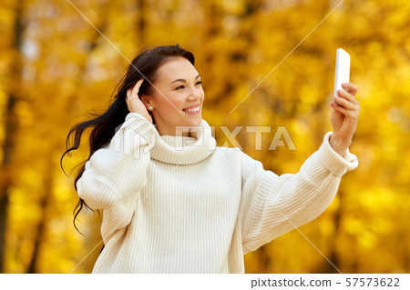 woman taking selfie by smartphone at autumn park 57573622