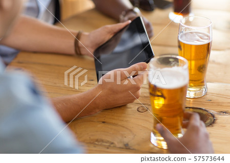 men with tablet computer drinking beer at bar men with tablet computer drinking beer at bar 57573644