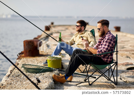 friends with smartphone and beer fishing on pier 57573802