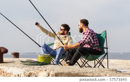friends fishing and taking selfie by smartphone 57573845