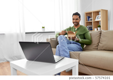 indian man with laptop eating takeout food at home 57574101