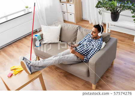 indian man in headphones after cleaning home indian man in headphones after cleaning home 57574276