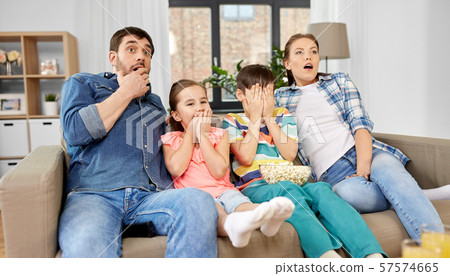 scared family with popcorn watching horror on tv 57574665