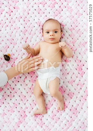 hand applying body lotion to baby girl's tummy hand applying body lotion to baby girl's tummy 57575029