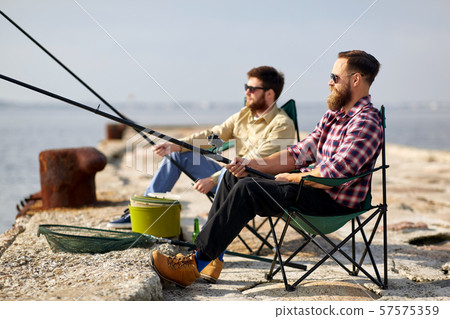 happy friends with fishing rods on pier 57575359