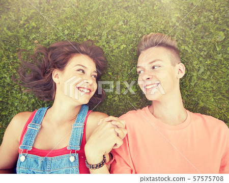 happy teenage couple lying on grass at summer happy teenage couple lying on grass at summer 57575708