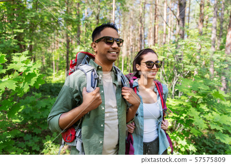 mixed race couple with backpacks hiking in forest 57575809