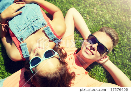 happy teenage couple lying on grass at summer happy teenage couple lying on grass at summer 57576406