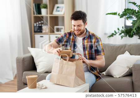 smiling man unpacking takeaway food at home smiling man unpacking takeaway food at home 57576413