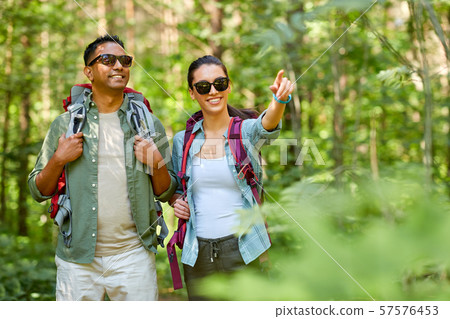 mixed race couple with backpacks hiking in forest 57576453