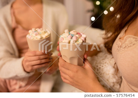 two women drinking hot chocolate with marshmallow 57576454