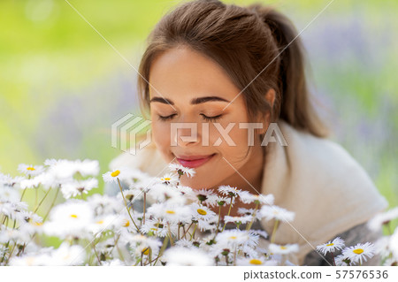 close up of woman smelling chamomile flowers close up of woman smelling chamomile flowers 57576536