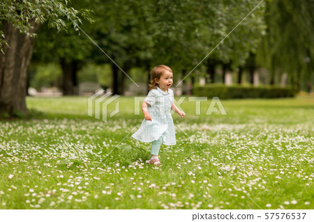 happy little baby girl running at park in summer 57576537