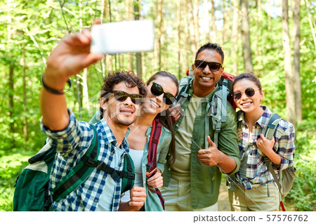 friends with backpacks hiking and taking selfie 57576762