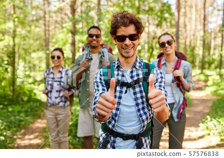 friends with backpacks showing thumbs up in forest 57576838