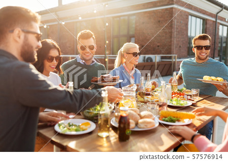 happy friends eating at barbecue party on rooftop happy friends eating at barbecue party on rooftop 57576914