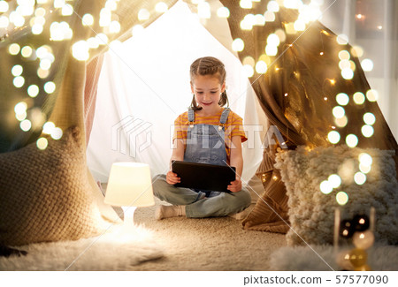 little girl with tablet pc in kids tent at home little girl with tablet pc in kids tent at home 57577090