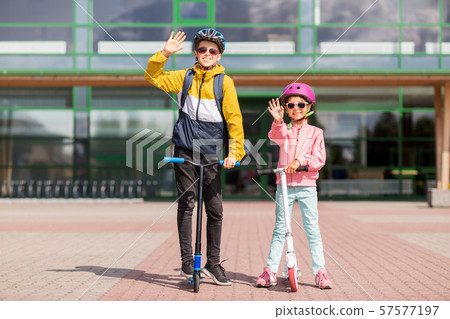 happy school children in helmets riding scooters 57577197