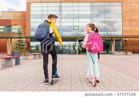 school children with backpacks riding scooters 57577198