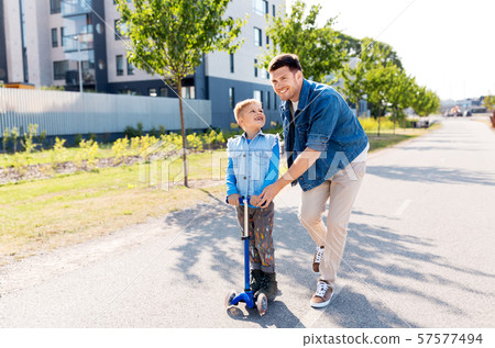 happy father and little son riding scooter in city 57577494