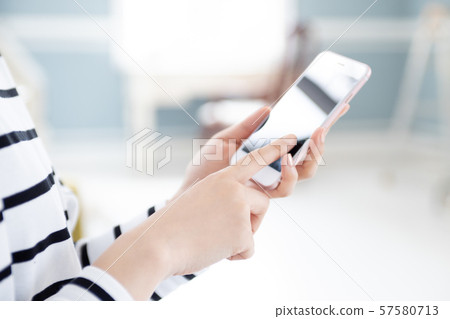 一個操作智能手機的年輕女子 57580713