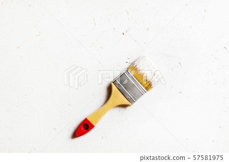 Construction brush with red handle on painted white plywood. Construction brush with red handle on painted white plywood. 57581975