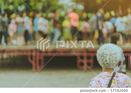 Back view of standing elder female watch Thai dance on the stage in the annual Songkran festival. 57582680