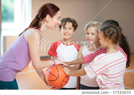 PE teacher and children smiling before starting basketball game PE teacher and children smiling before starting basketball game 57583070