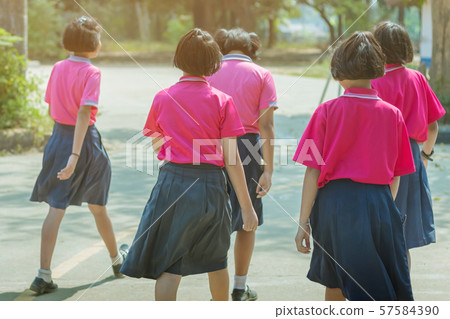 Back view of happiness primary girl students in pink shirt and blue skirt walk to classrooms with their friends. 57584390