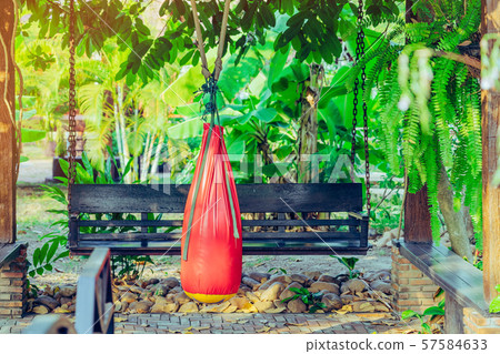 Red sand bag for Muay Thai hanging in the garden 57584633